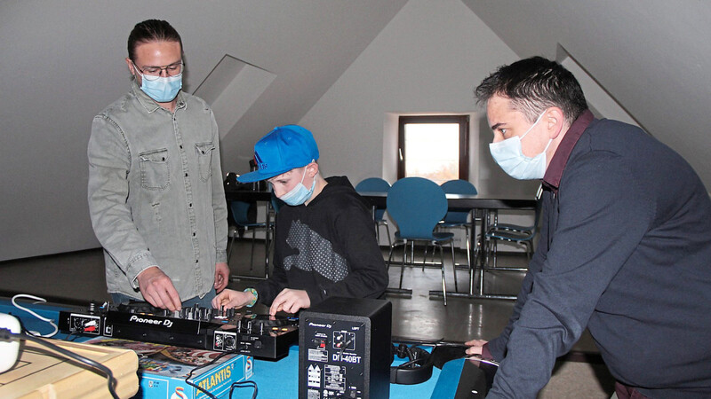 DJ Sebastian Gabler (links) probiert mit Linus das Scratchen aus; rechts Jugendpfleger Samu Koch.