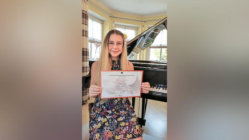 Veronika Troiber präsentiert stolz ihre Urkunde über ihren Erfolg beim "Euplayy"-Klavierwettbewerb.