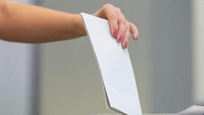 Eine Wählerin wirft bei der Stimmabgabe ihren Wahlzettel in eine Wahlurne.