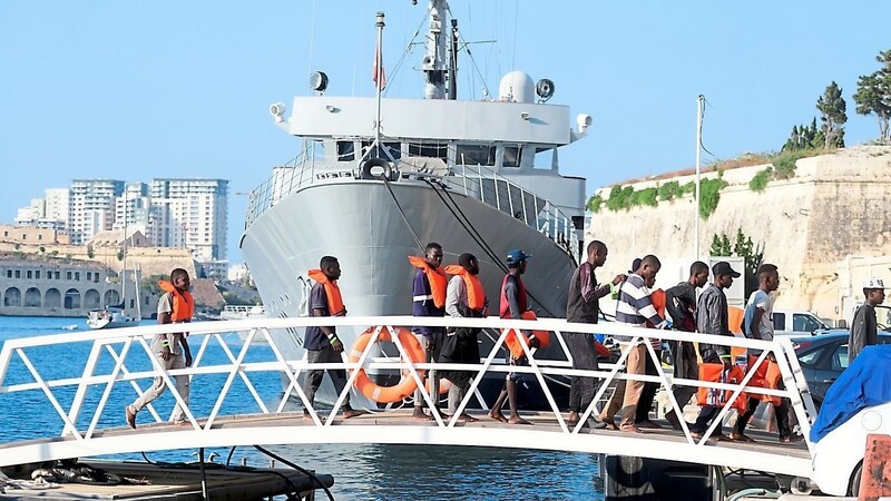 Migranten kommen an einem Marinestützpunkt in Malta an.