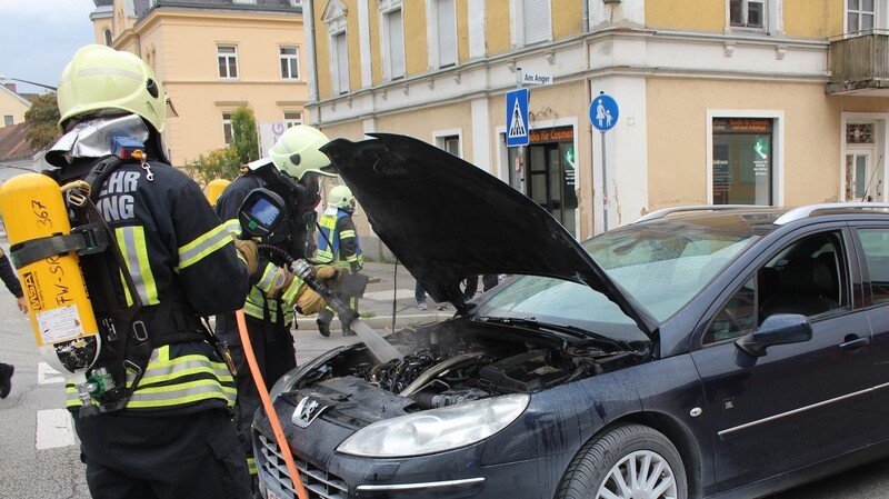 Die Feuerwehrmänner bei den Nachlöscharbeiten im Motorraum des Fahrzeugs.