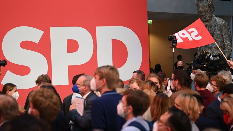 Anhänger der SPD schauen im Willy-Brandt-Haus auf die ersten Ergebnisse der Bundestagswahl, die auf einem Display angezeigt werden.