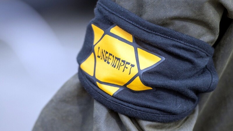Ein Demonstrant trägt eine Armbinde mit einem gelben Stern, der an einen Judenstern erinnern soll.