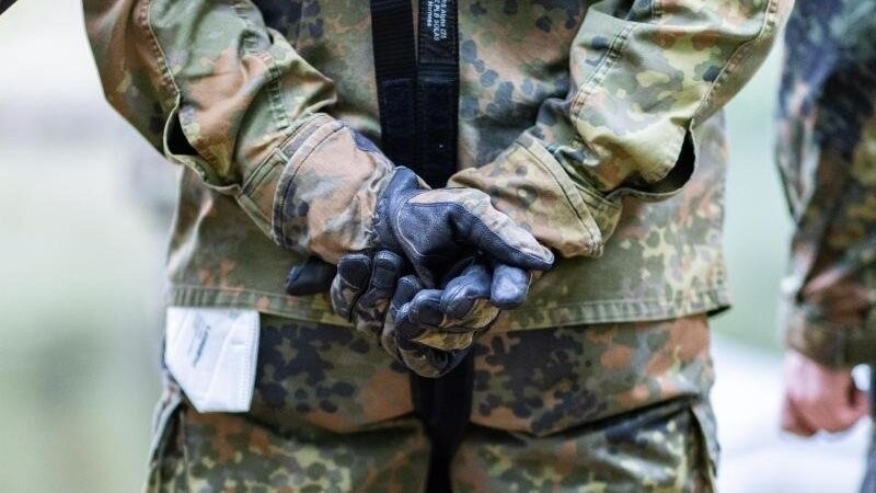 Bundeswehrsoldaten stehen mit überkreuzten Händen zusammen.