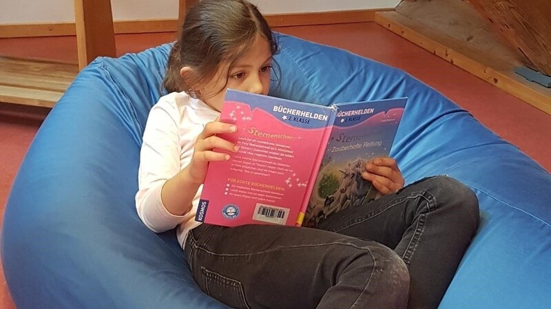 Viola liest gemütlich im Knautschkissen der Altfraunhofener Gemeindebücherei. Neben Büchern gibt es hier auch andere Medien.