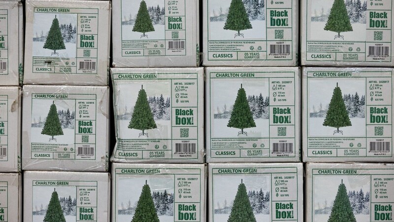 Verpackte Weihnachtsbäume aus Kunststoff (PVC) in einem Baumarkt.