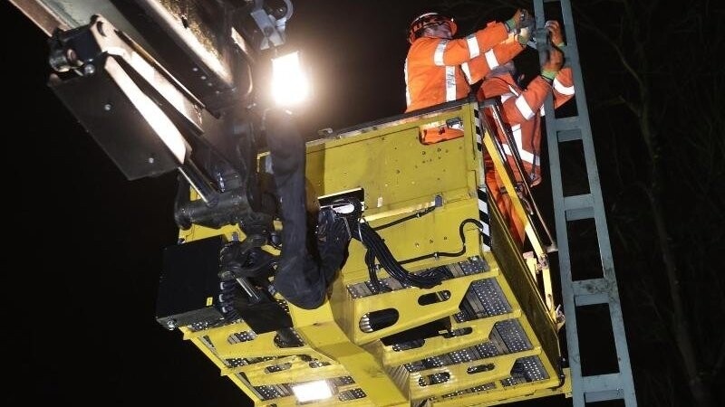 Mitarbeiter der Deutschen Bahn reparieren die Aufhängung des stromführenden Strangs einer Oberleitung nach dem Sturm.