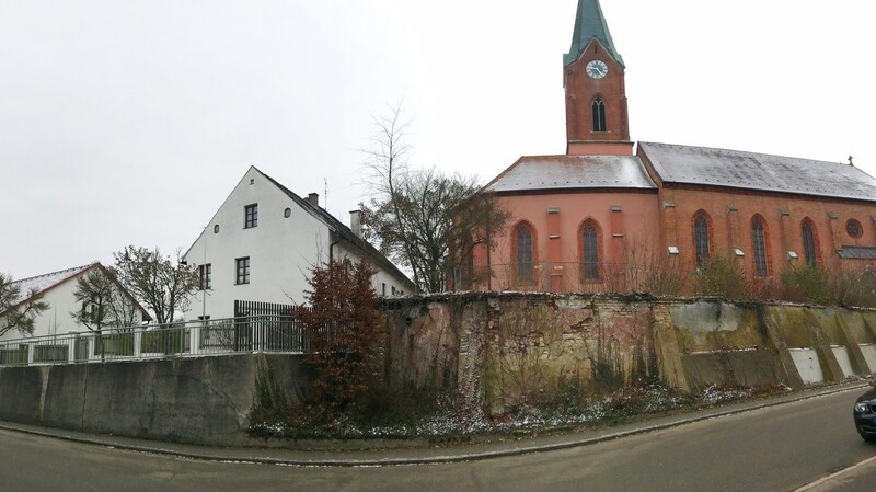 Die Attinger Hauptstraße mit dem Kindergarten (links), dem Pfarrhaus (Mitte) und der maroden Kirchhofmauer vor der Pfarrkirche.