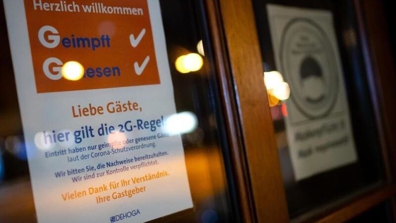 Ein Schild mit der Aufschrift "Liebe Gäste, hier gilt die 2G-Regel" hängt an der Tür von einem Wirtshaus in München.