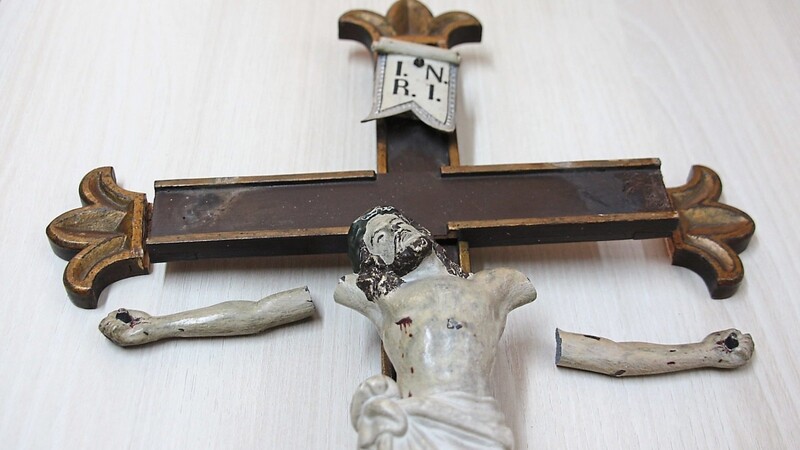 Zerschmettert ist die Jesusfigur am Kreuz und seine Verzierungen.