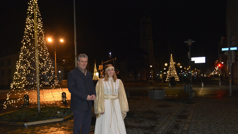 Bürgermeister Hans Schmalhofer und Christkindl Nele Weigel am weihnachtlich beleuchteten Stadtplatz.