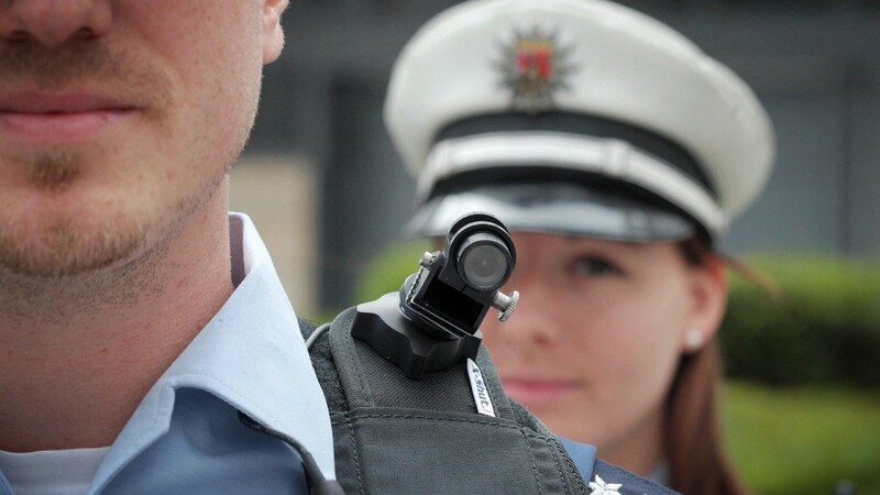 Ein Polizist trägt am 08.06.2015 bei einem Pressetermin im Innenministerium in Mainz (Rheinland-Pfalz) eine mobile Miniatur-Videokamera auf seiner Schulter.