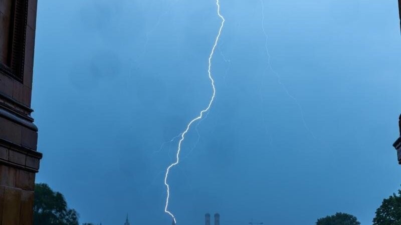 Ein Blitz schlägt in den Turm des Münchner Rathauses ein.