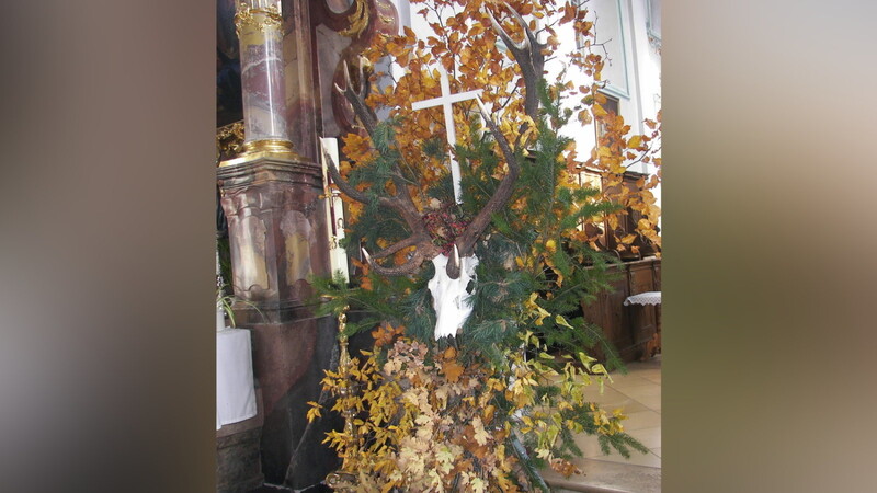 Das machtvolle Geweih mit dem Kreuz zwischen den Stangen erinnert an die Legende von der Bekehrung des heiligen Hubertus.