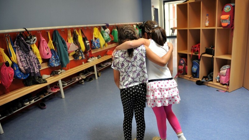 Zwei Mädchen gehen in einer Ganztagesschule in München Arm in Arm durch die Schule.