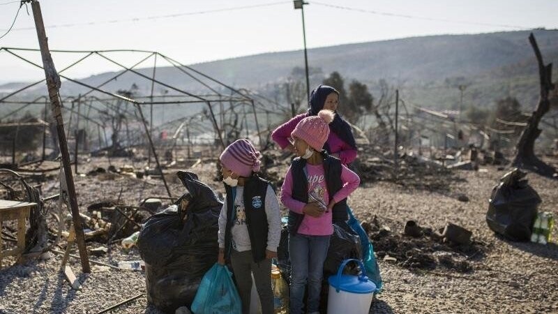 Eine Familie steht innerhalb des ausgebrannten Flüchtlingslagers Moria. Mehrere Brände haben das Lager fast vollständig zerstört.
