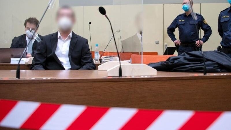 Der wegen versuchten Mordes in 31 Fällen, schwerer Brandstiftung und Vorbereitung einer schweren staatsgefährdenden Gewalttat angeklagte Mann (2.v.l) sitzt vor Prozessbeginn mit seinem Anwalt im Landgericht in München im Verhandlungssaal.