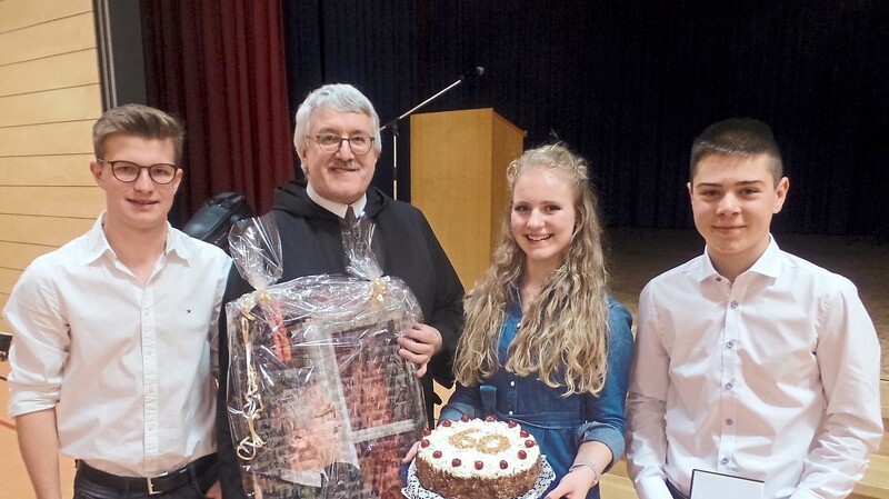 Pater Erhard freute sich über die Geschenke, die ihm die Schülersprecher Lea Bumberger, Florian Nickl und Benedikt Weinberger übergaben.