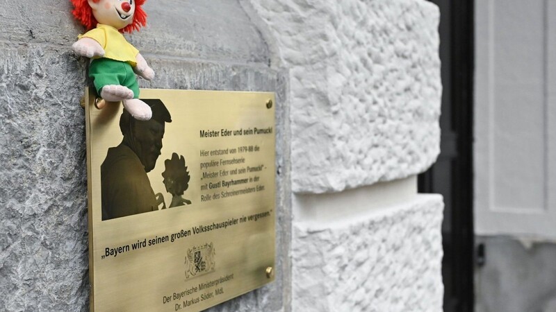 Eine Pumuckl-Figur sitzt auf einer Gedenktafel zu Ehren des Schauspielers Gustl Bayrhammer.