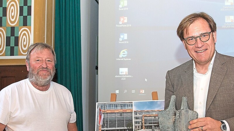 Bezirkstagsvizepräsident Dr. Thomas Pröckl (links) und Hubert Huber, Vorsitzender des BBK Niederbayern, mit dem Gewinner-Entwurf des Ehepaars Michaela und Florian Geissler aus Hörlkam.