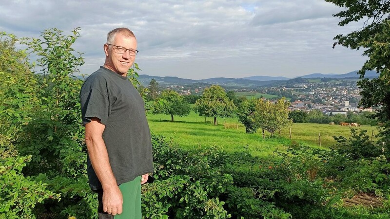 Bio-Landwirt Klaus Prestel inmitten seines Obstgartens mit Blick auf seine grasende Herde.