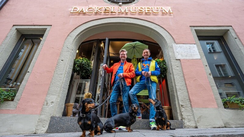Seppi Küblbeck (r) und Oliver Storz mit ihren drei Dackeln vor dem Dackelmuseum.