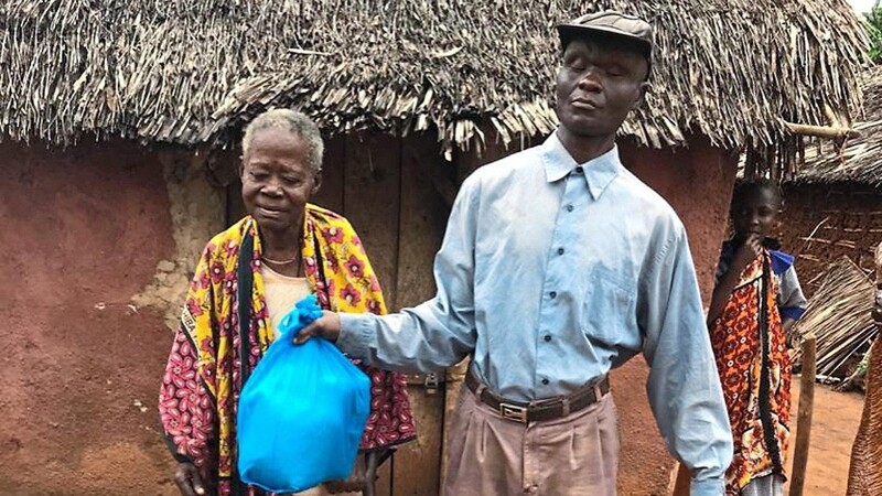 Pastor Peter übergibt einer an Lepra erkrankten, blinden Frau ein Hilfspaket der Ukunda-Hilfe.