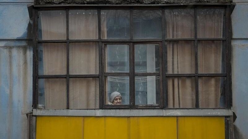 Eine Frau blickt aus dem Fenster eines Hauses in Sjewjerodonezk im Osten der Ukraine.