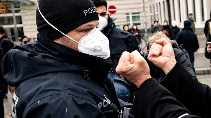 Ein Teilnehmer einer verbotenen Demonstration von Gegnern der Corona-Regeln streckt seine Fäuste einem Polizisten entgegen. DIe Gewalt gegen EInsatzkräfte hat auf dem Papier abgenommen. Gewerkschafter sehen keine Entspannung.