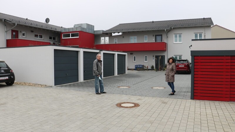 Karin und Georg Bühler vor dem Wohnkomplex mit den Garagen und dem umlaufenden Laubengang (rot), der die Wohnungen im ersten Stock verbindet.