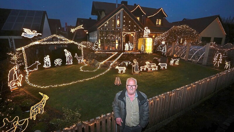 Josef Glogger steht am Gartenzaun seines weihnachtlich geschmückten Hauses. Knapp 30 000 LED-Lichter wurden dort von ihm verbaut, um eine Krippe darzustellen.