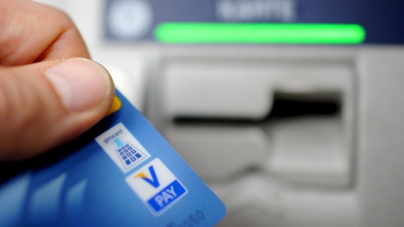 Ein Bankkunde hebt mit seiner Girokarte Bargeld von einem Geldautomaten ab. Spätestens ab Mitte 2016 soll in Deutschland jeder das Recht auf ein Bankkonto haben - auch Obdachlose und Flüchtlinge.