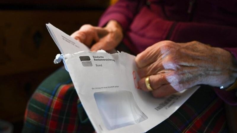 Eine Seniorin hält ihren Rentenbescheid in der Hand.