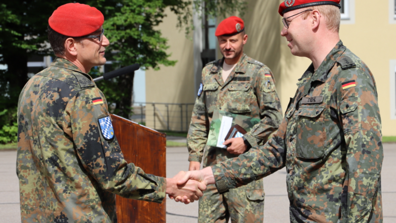 Oberstleutnant Seifert (links) übergibt Hauptmann Jan Diehl (rechts) den Coin des Kommandeurs, im Hintergrund Hauptmann Thomas Unholzer, S1-Offizier im Panzerpionierbataillon 4.