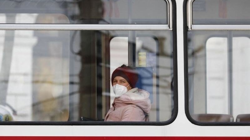 Eine Frau mit Mund-Nasen-Schutz sitzt in einer Straßenbahn.
