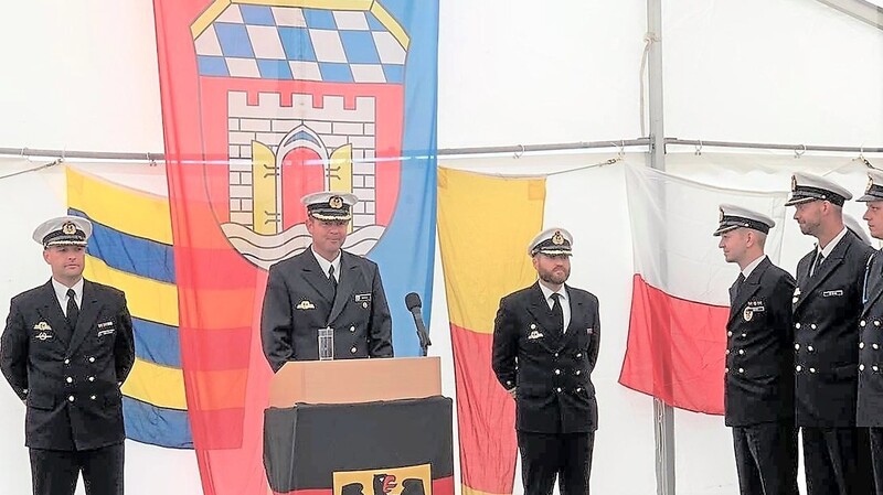 Kommandeur Torsten Eidam (M.) übergibt das Kommando von Rouven Grünhagen (r.) an Bernd Abshagen (l.). Im Hintergrund die Deggendorfer Fahne.