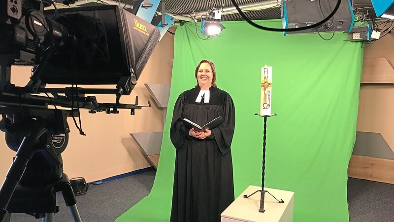 Pfarrerin Veronika Mavridis wurde vor einer grünen Leinwand gefilmt, sodass später die Dreieinigkeitskirche als Hintergrund eingeblendet werden kann.