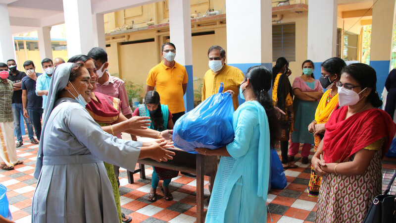 Schwester Kala (l.) und ihre Helfer verteilen Tüte mit Grundnahrungsmitteln an die Familien der Patenkinder.