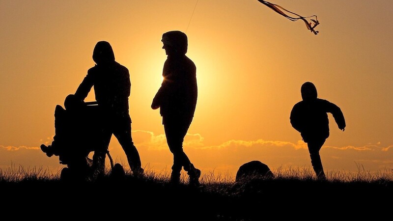 Eine Familie spaziert in den Sonnenuntergang. Wie man dem Alltagsstress mit ein bisschen Kreativität und einfachen Tipps entkommen kann, darum geht es diesen Winter im Familienstützpunkt.