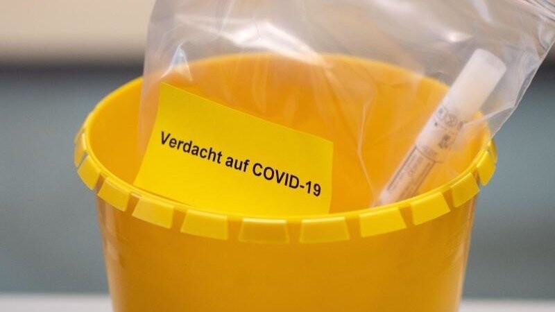 Ein Teströhrchen liegt in einer Tüte mit der Aufschrift "Verdacht auf COVID-19". (Symbolbild).