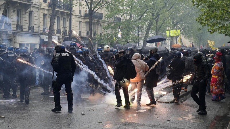 Ein Gegenstand explodiert zwischen Polizisten am Rande einer Demonstration am Tag der Arbeit.