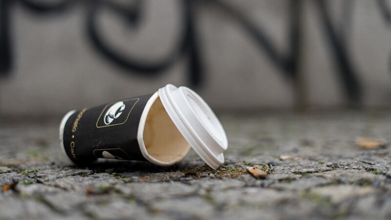 Ein achtlos weggeworfener Einweg-Kaffeebecher liegt auf dem Boden
