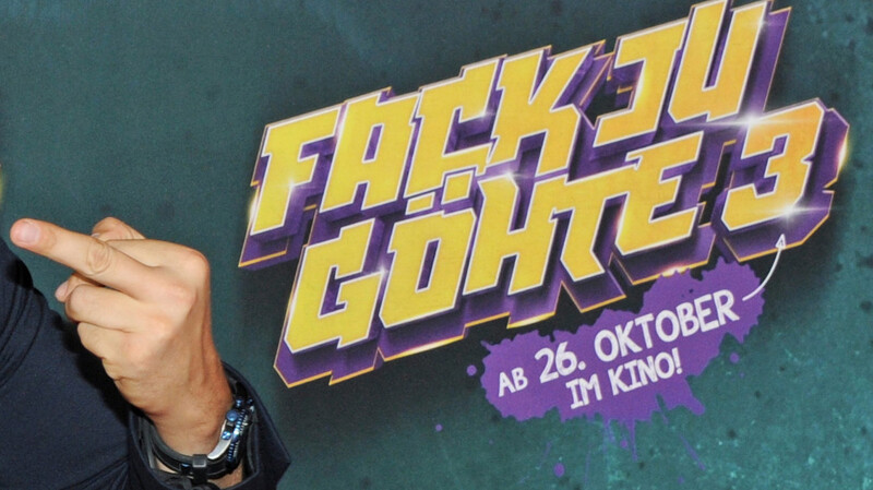 Ein Mann zeigt zur Filmpremiere von "Fack ju Göhte 3" in München vor dem Schriftzug des Filmtitels den Mittelfinger.