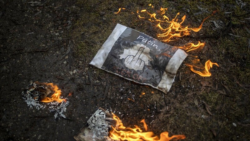 Demonstranten verbrennen während eines Protest gegen den Angriff Russlands auf die Ukraine vor der russischen Botschaft russischee Pässe und eine Botschaft an den Putin.