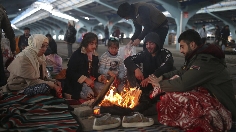 Migranten sitzen auf dem Gelände eines Marktes nahe der türkisch-griechischen Grenze an einem Feuer.