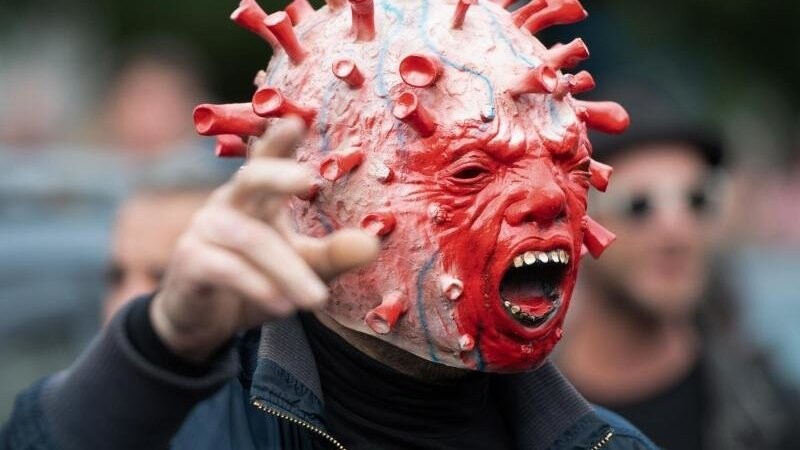Bei der Anti-Corona-Demo in Berlin hat sich ein Mann eine besondere Maske gebastelt: ein Virus-Kopf mit Wutbürger-Ausdruck.