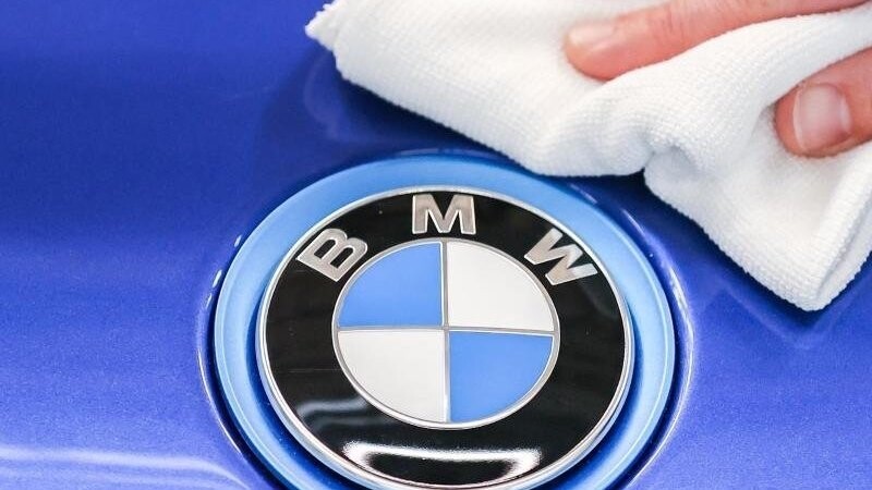 Ein Mitarbeiter von BMW poliert mit einem Tuch das Logo von einem BMW.