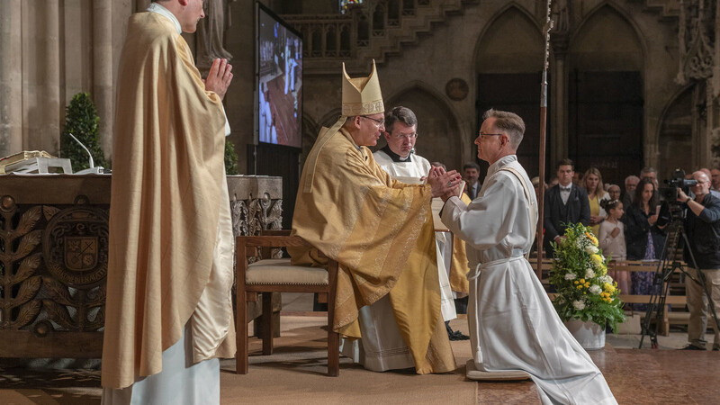 Bischof Voderholzer weiht Wolfgang Weyer (kniend) zum Priester.