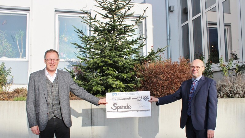 Bürgermeister Christian Dobmeier (links) nimmt das großzügige Weihnachtsgeschenk in Form einer finanziellen Unterstützung für die Grund- und Mittel-Schule, überreicht von Raiffeisen-Zweigstellenleiter Bernhard Maier, entgegen.