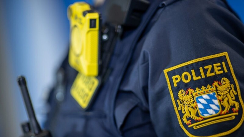 Eine Polizistin trägt während einer Pressekonferenz ein Polizei-Abzeichen neben einer Body-Cam.